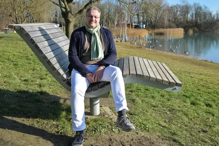 Ralf Marohn sitzt auf einer Ruhebank am See